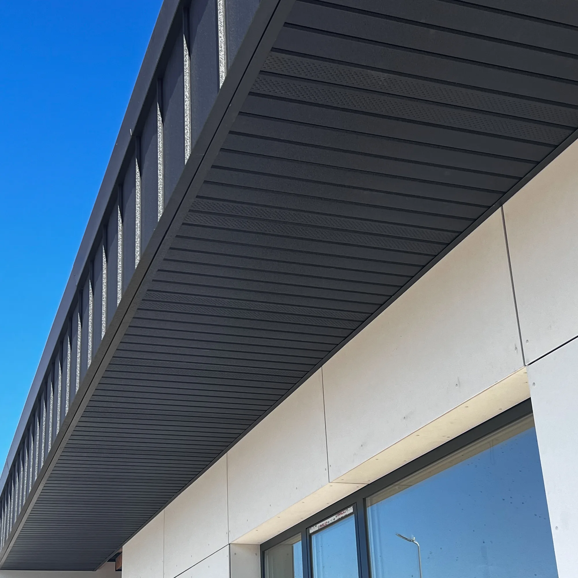 Streașină placată cu lambriu metalic negru, cu panouri perforate pentru aerisire